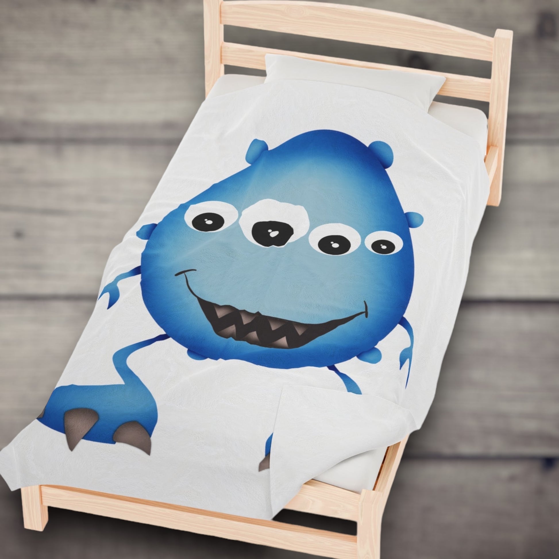 Cute Blue Monster Kids Plush Blanket on a bed.