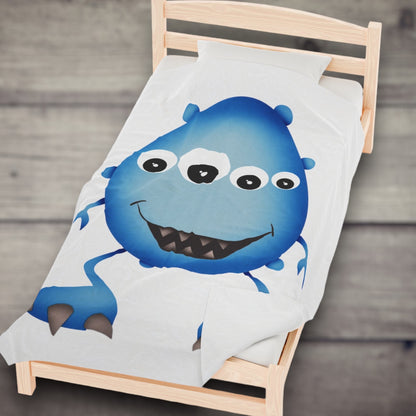 Cute Blue Monster Kids Plush Blanket on a bed.