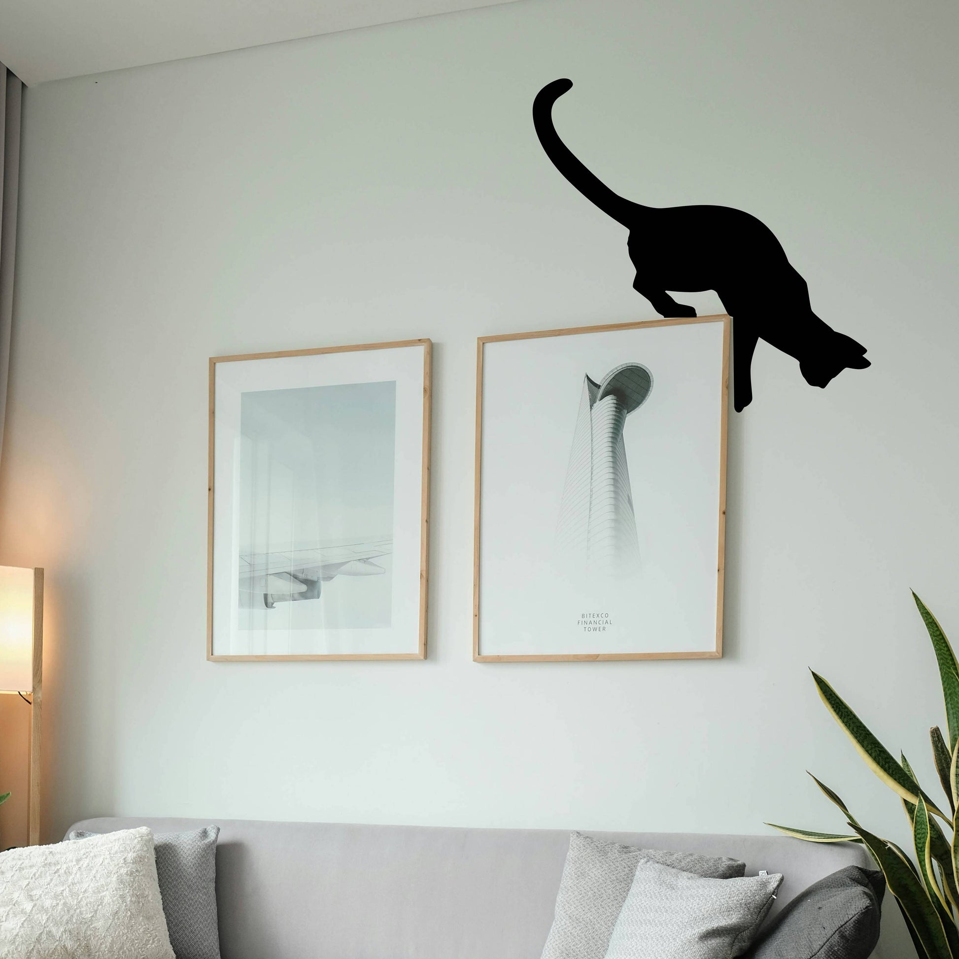 Metal cat sculpture perched on picture frame corners
